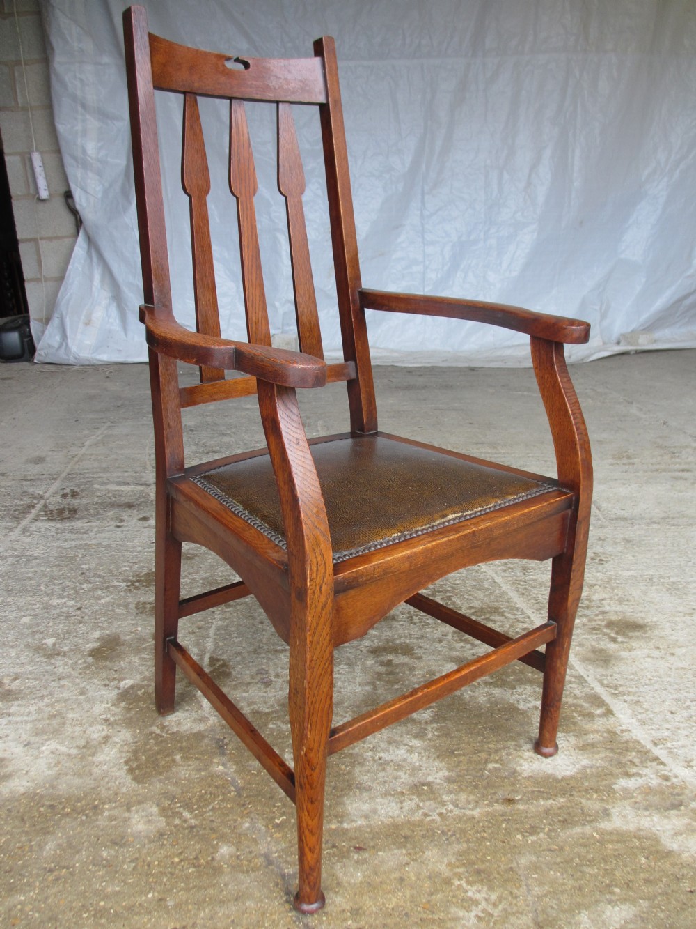 Arts & Crafts oak splat back carver open armchair with spear shaped splats, shaped arms and forelegs with turned tapering feet, box stretcher and studded padded leather seat (circa 1900)