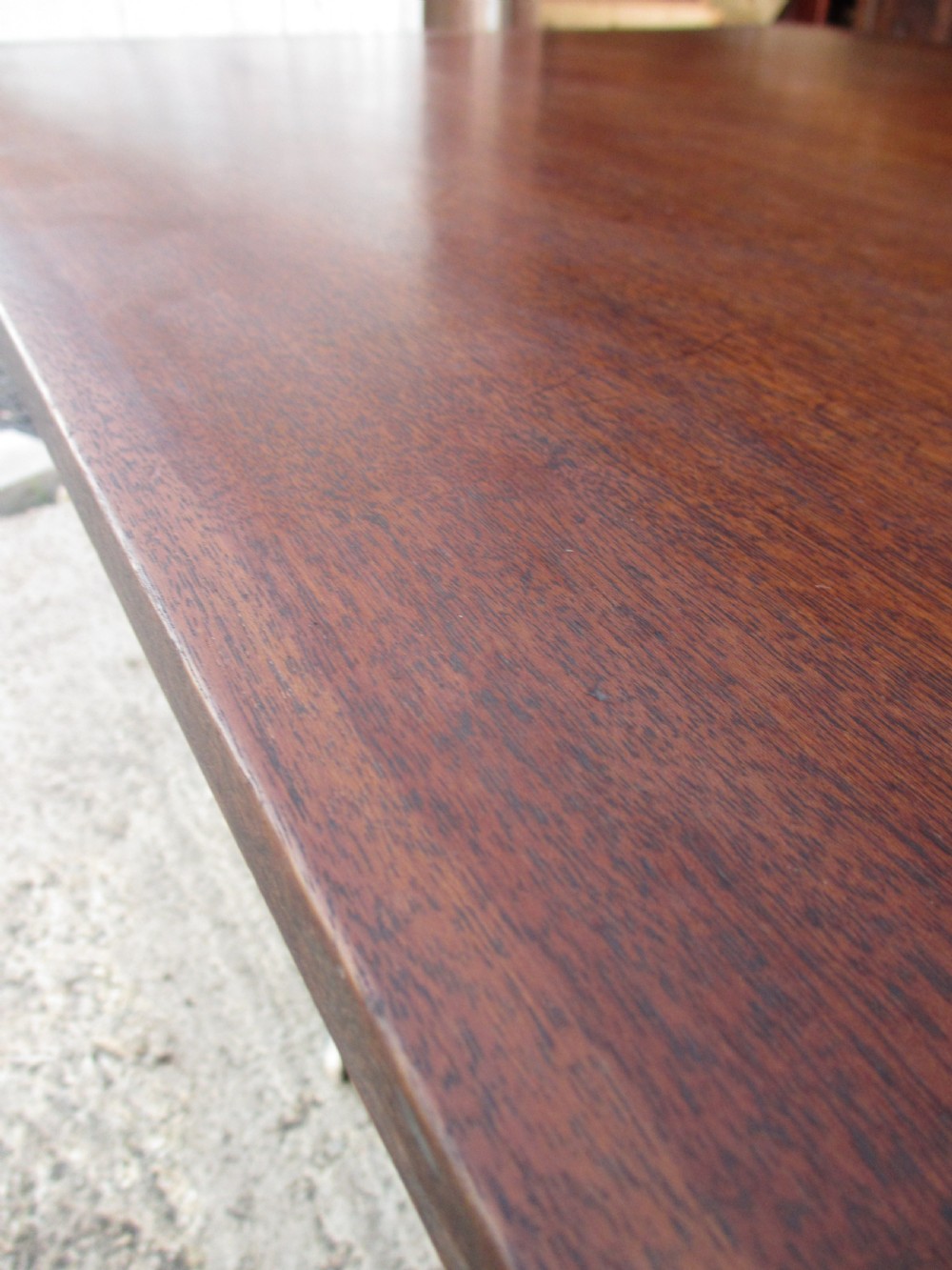 A 19th-century mahogany rectangular tilt-top dining table supported by a turned central pedestal with four splayed legs fitted with brass castors. View II