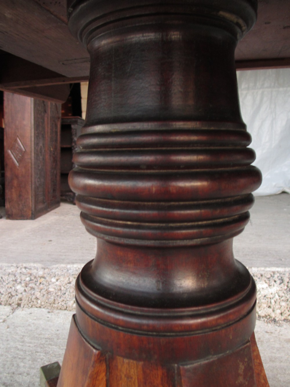 A 19th-century mahogany rectangular tilt-top dining table supported by a turned central pedestal with four splayed legs fitted with brass castors. View IV