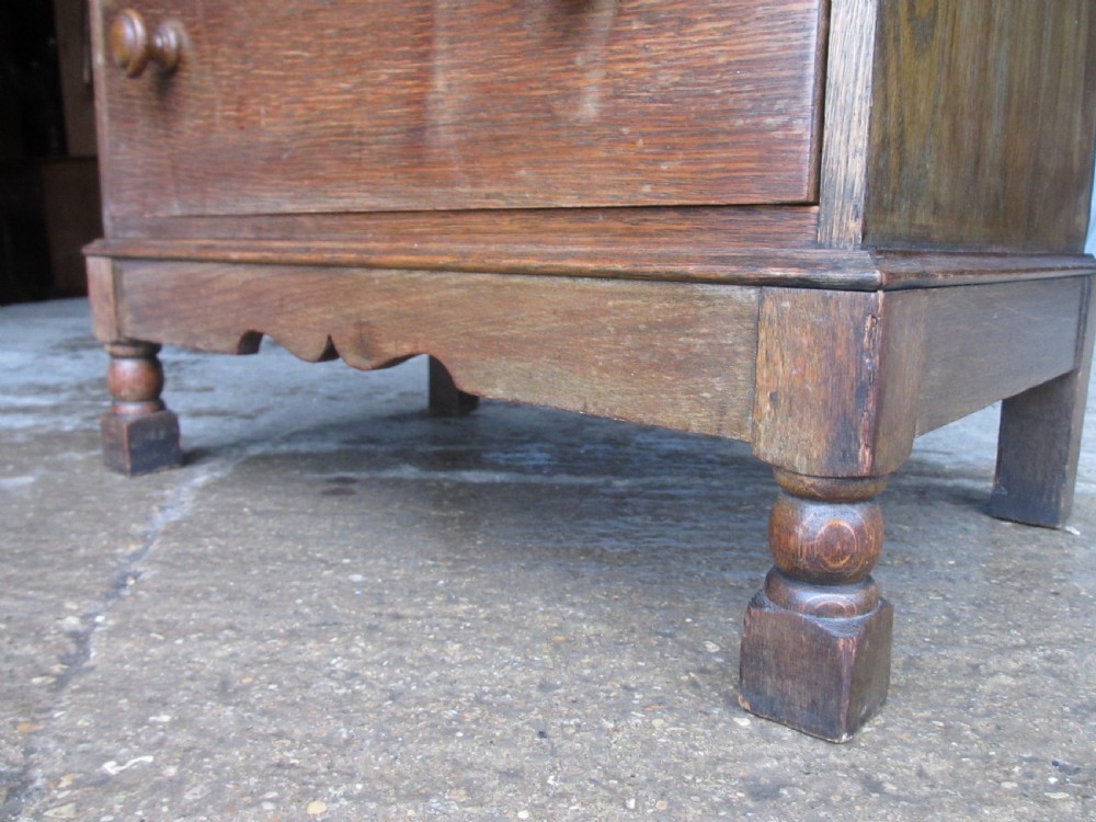 A narrow Edwardian oak bureau bookcase with twin glazed doors on the upper section above a fall-front writing desk and three drawers with wooden bun handles. View VI