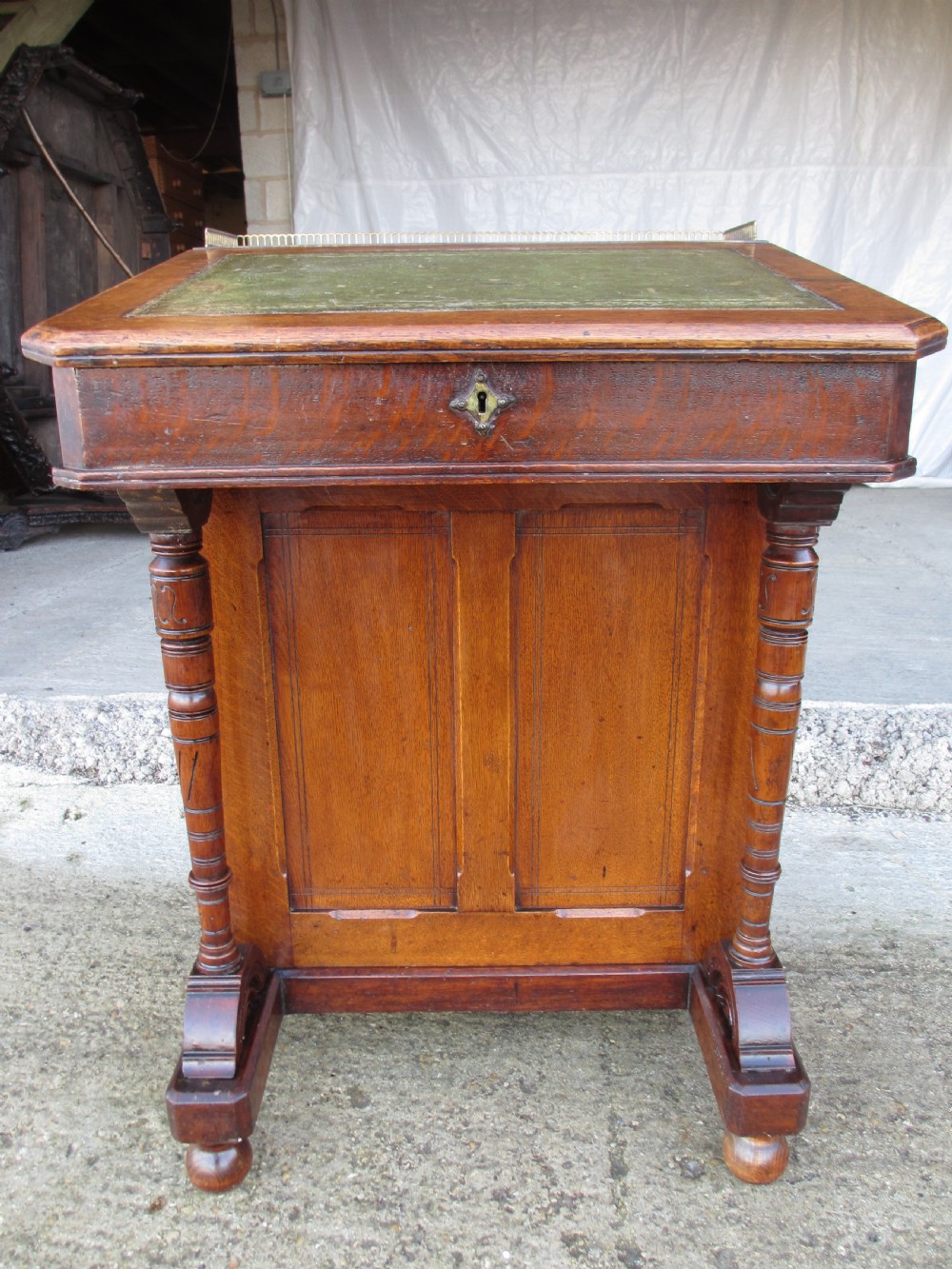 A Victorian oak davenport desk featuring a green leather writing surface, brass gallery rail, and turned front columns. View II