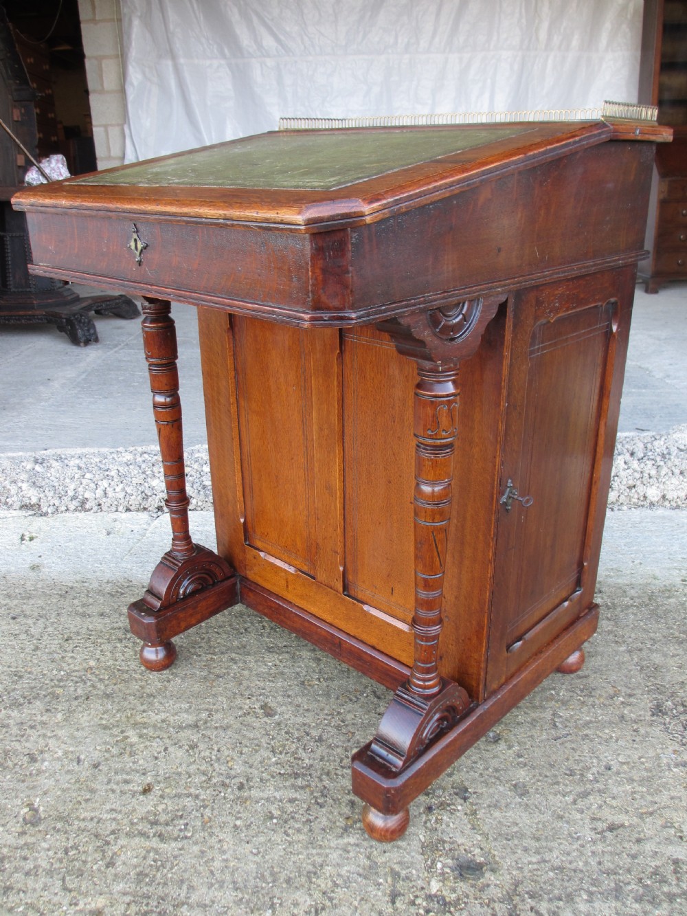 A Victorian oak davenport desk featuring a green leather writing surface, brass gallery rail, and turned front columns. View III