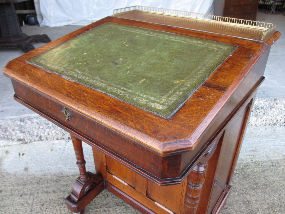 A Victorian oak davenport desk featuring a green leather writing surface, brass gallery rail, and turned front columns. View IV