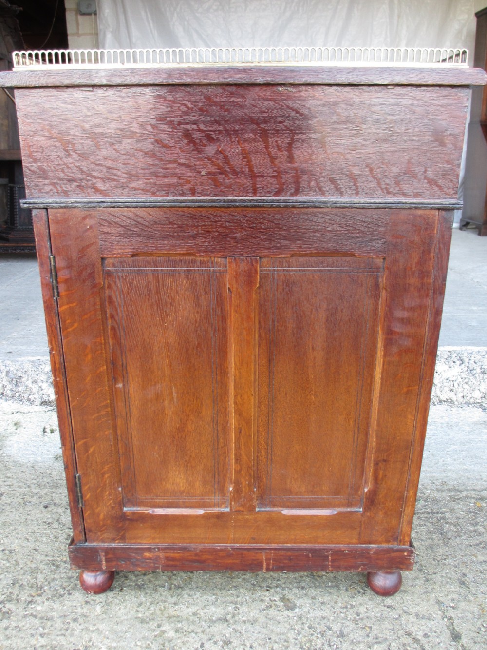 A Victorian oak davenport desk featuring a green leather writing surface, brass gallery rail, and turned front columns. View XX