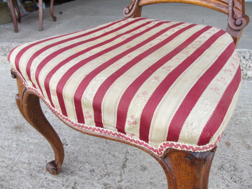 A pair of 19th-century oak balloon back dining chairs featuring red and cream striped upholstery, carved scroll details, and cabriole legs. View IX