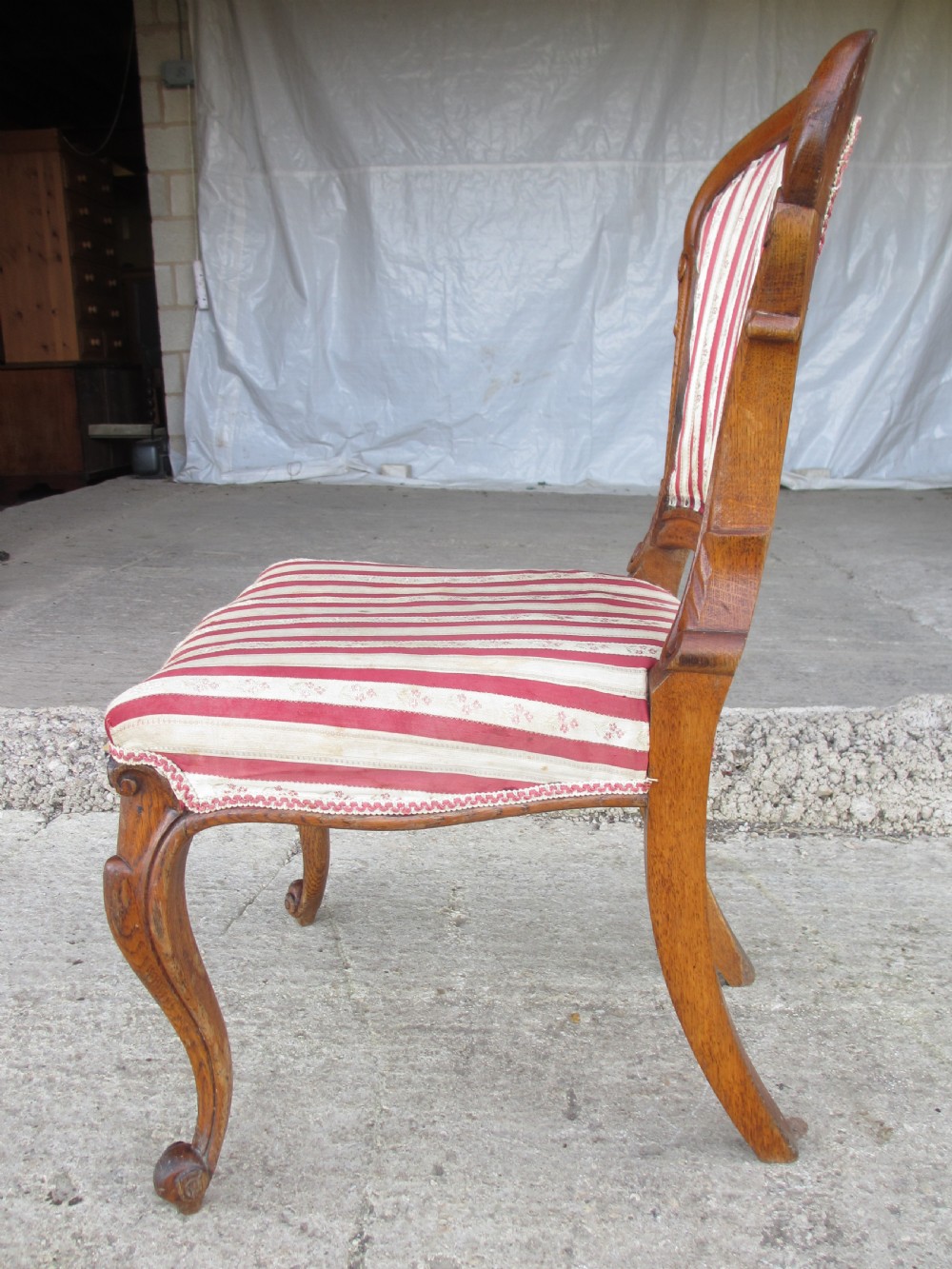A pair of 19th-century oak balloon back dining chairs featuring red and cream striped upholstery, carved scroll details, and cabriole legs. View XV