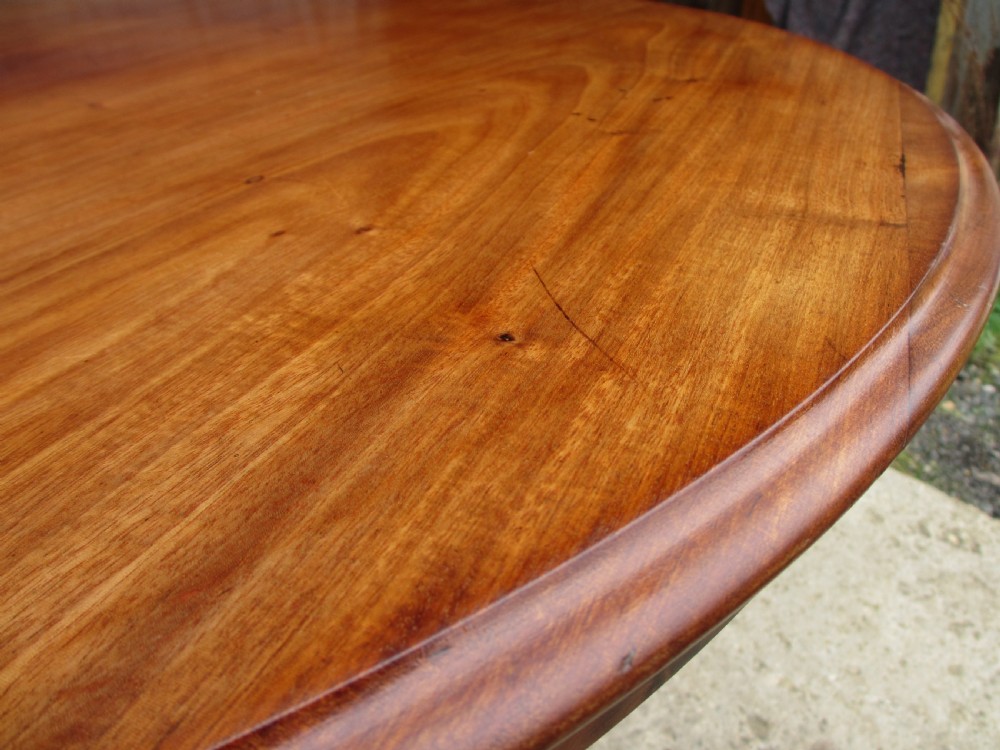 Victorian mahogany circular tilt top table with tripod scrolled legs on castors  View III