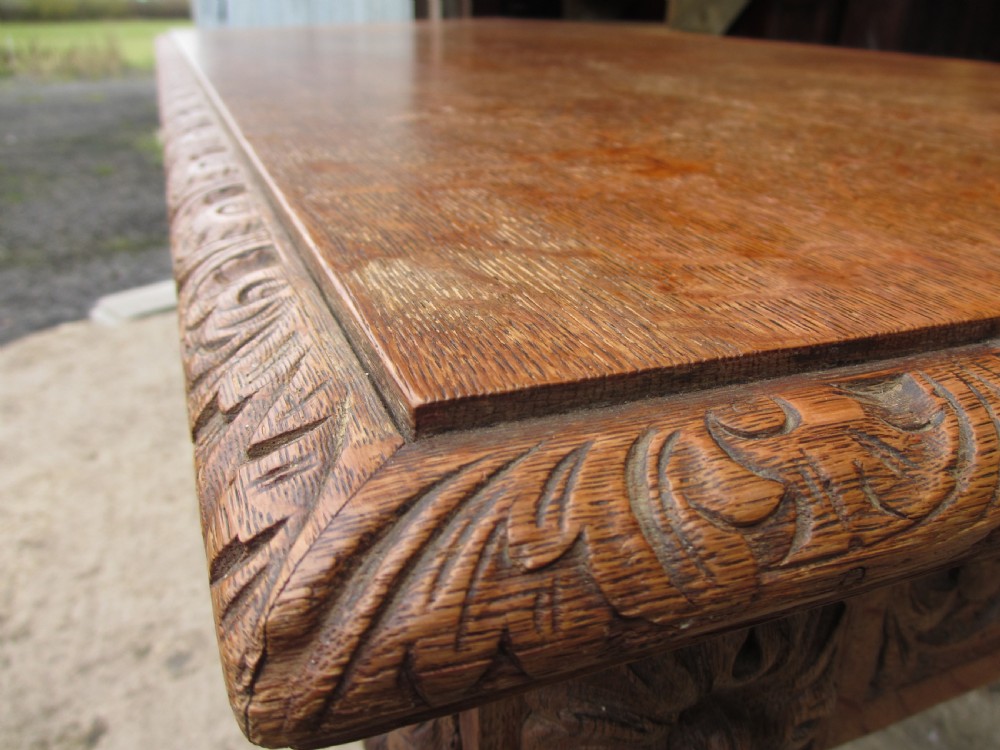 Victorian carved heavy oak dining table with lion heads and floral and leaf frieze on solid oak supports View II