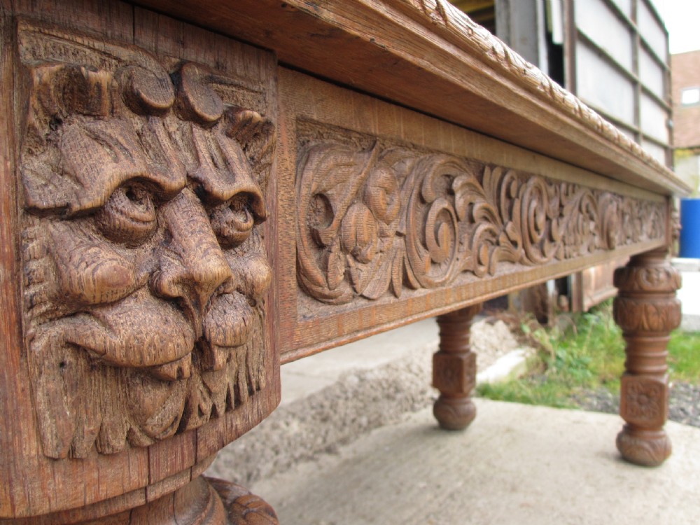 Victorian carved heavy oak dining table with lion heads and floral and leaf frieze on solid oak supports View III