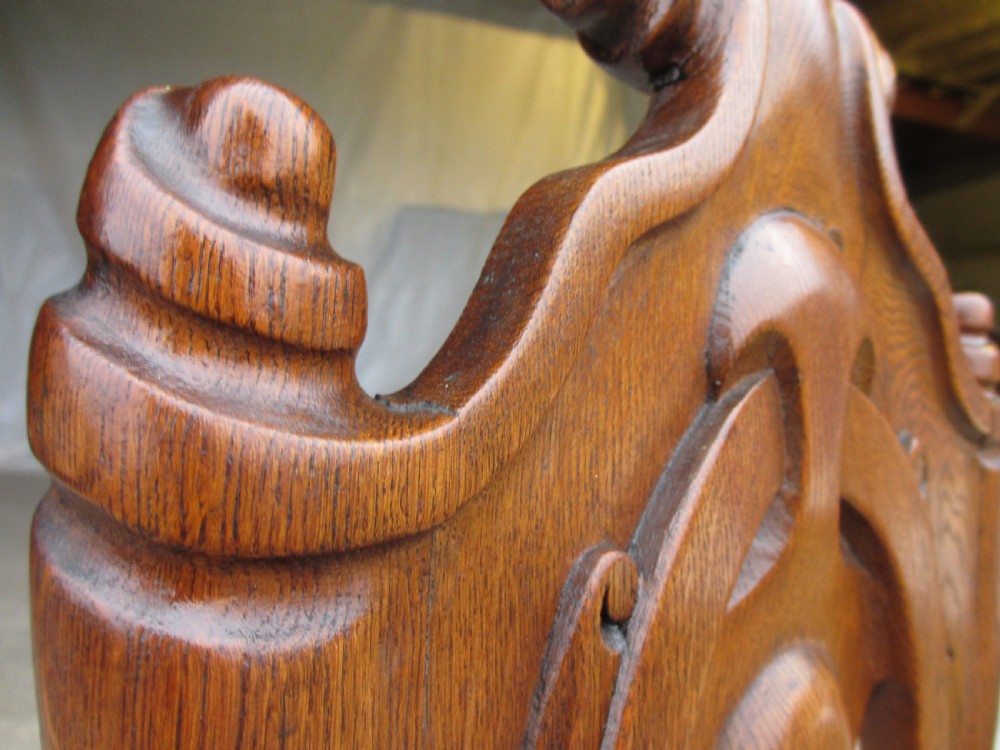 A pair of Victorian carved golden oak hall chairs featuring openwork shield backs with central cartouches, solid wooden seats, and cabriole front legs. View V