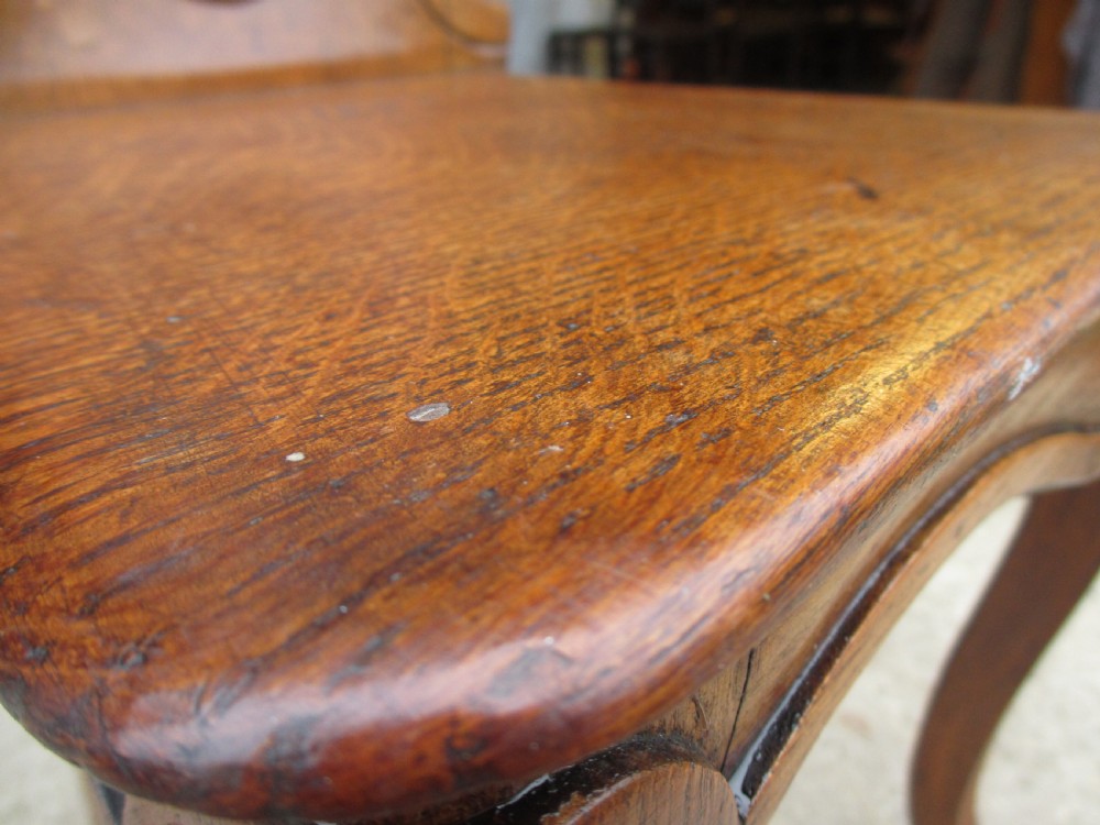 A pair of Victorian carved golden oak hall chairs featuring openwork shield backs with central cartouches, solid wooden seats, and cabriole front legs. View VIII