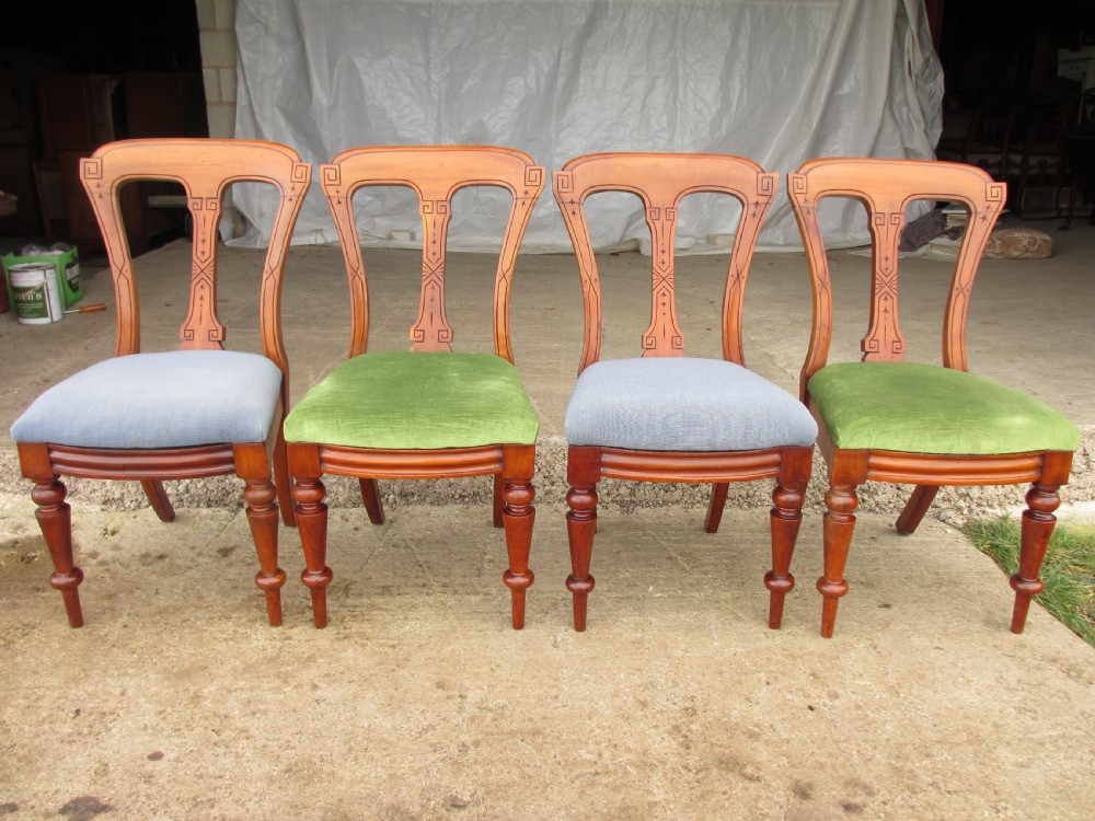 A set of four antique mahogany dining chairs with carved vase splats, inlaid details, turned front legs, and fabric drop-in seats.