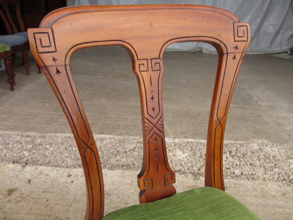 A set of four antique mahogany dining chairs with carved vase splats, inlaid details, turned front legs, and fabric drop-in seats. View V