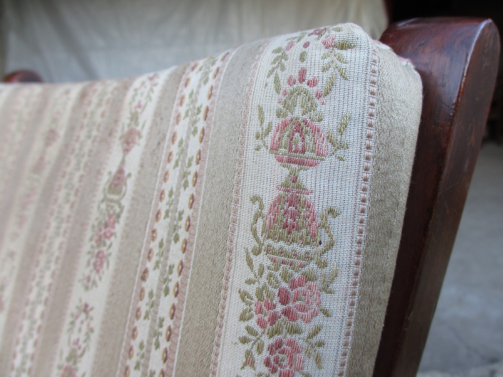 A 19th-century dark mahogany armchair featuring turned side spindles, beige striped upholstery, an adjustable reclining backrest, and brass castors. View III