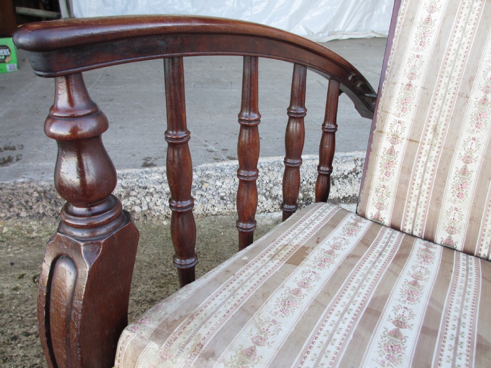 A 19th-century dark mahogany armchair featuring turned side spindles, beige striped upholstery, an adjustable reclining backrest, and brass castors. View IV