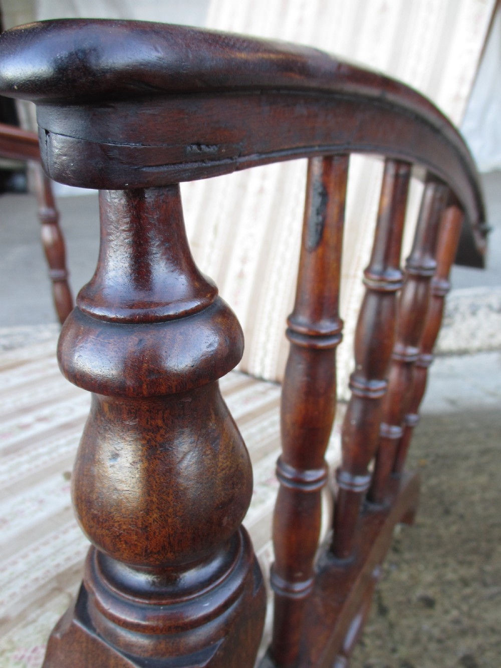 A 19th-century dark mahogany armchair featuring turned side spindles, beige striped upholstery, an adjustable reclining backrest, and brass castors. View V