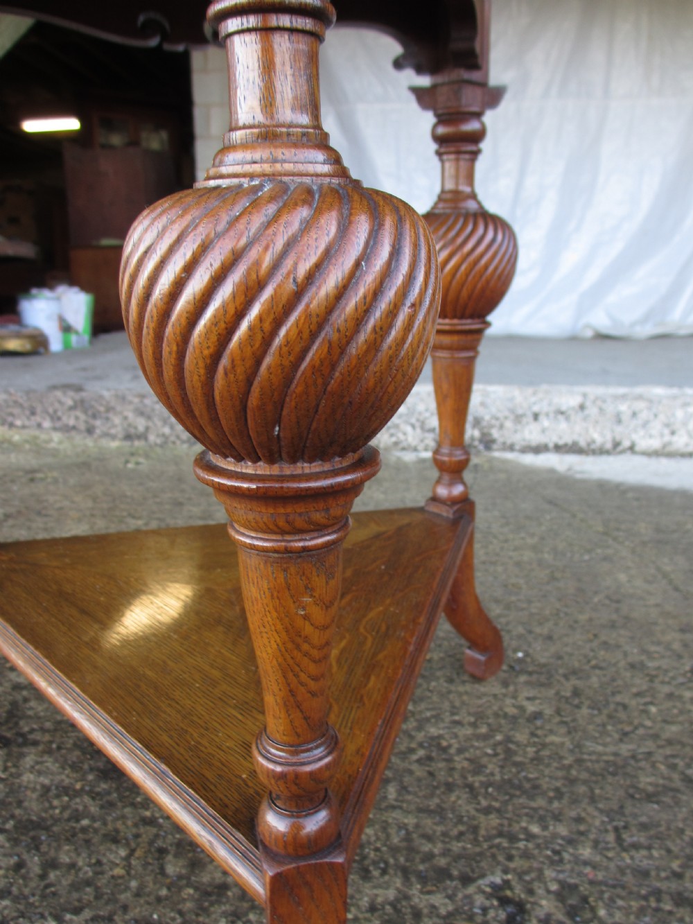 An Edwardian oak circular occasional table featuring three carved spiral-bulb legs, a shaped apron, and a lower triangular tier shelf. View VIII