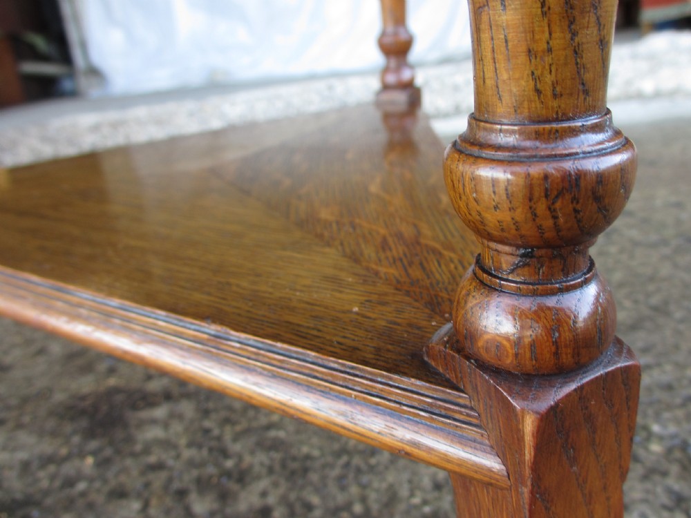 An Edwardian oak circular occasional table featuring three carved spiral-bulb legs, a shaped apron, and a lower triangular tier shelf. View XI