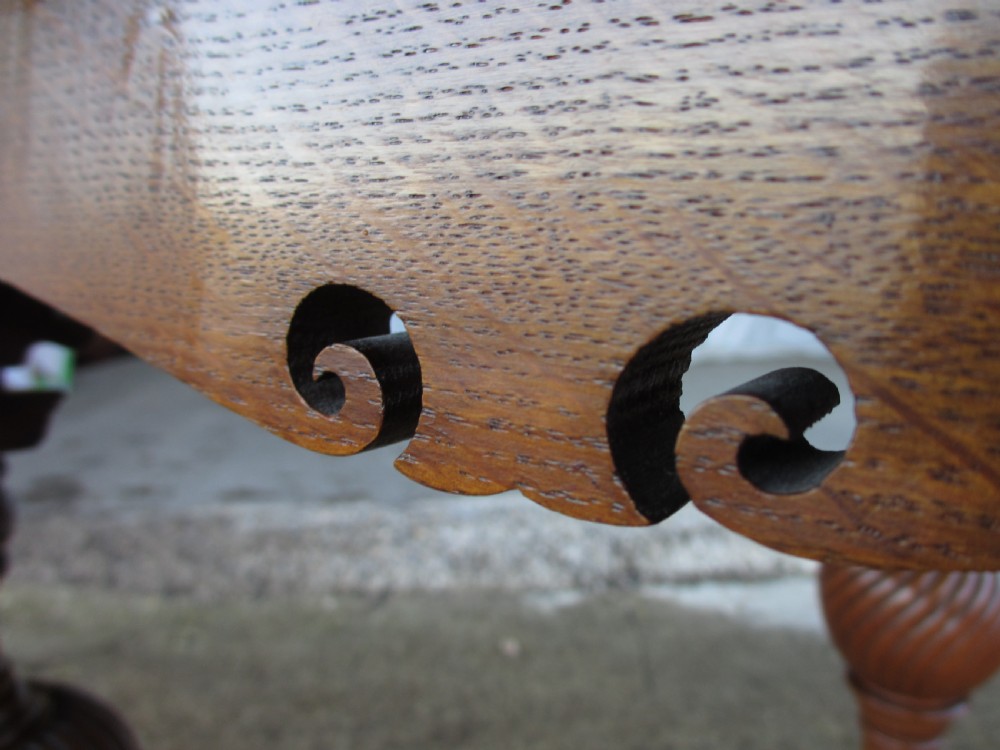 An Edwardian oak circular occasional table featuring three carved spiral-bulb legs, a shaped apron, and a lower triangular tier shelf. View XII