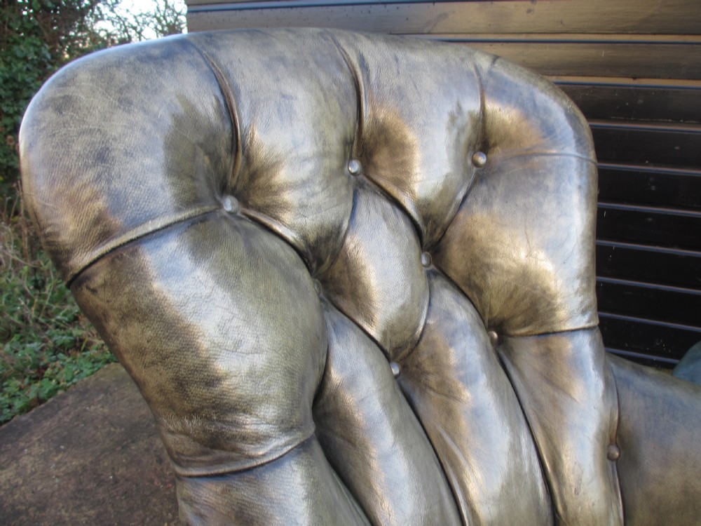 A Victorian conversation sofa upholstered in buttoned dark green leather featuring a carved rosewood frame with brass castors. View VII