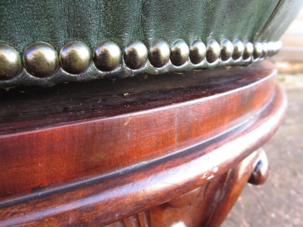 A Victorian conversation sofa upholstered in buttoned dark green leather featuring a carved rosewood frame with brass castors. View XI