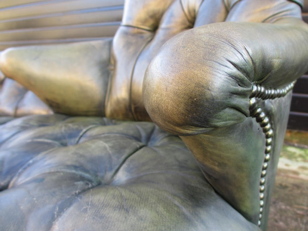 A Victorian conversation sofa upholstered in buttoned dark green leather featuring a carved rosewood frame with brass castors. View XII