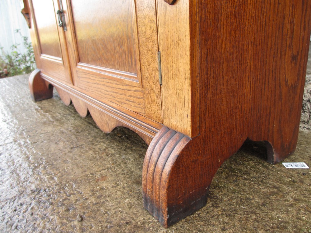 An Edwardian golden oak bureau bookcase featuring a two-door glazed upper section, a fall-front slanted writing desk, and a lower cabinet base with carved supports. View III