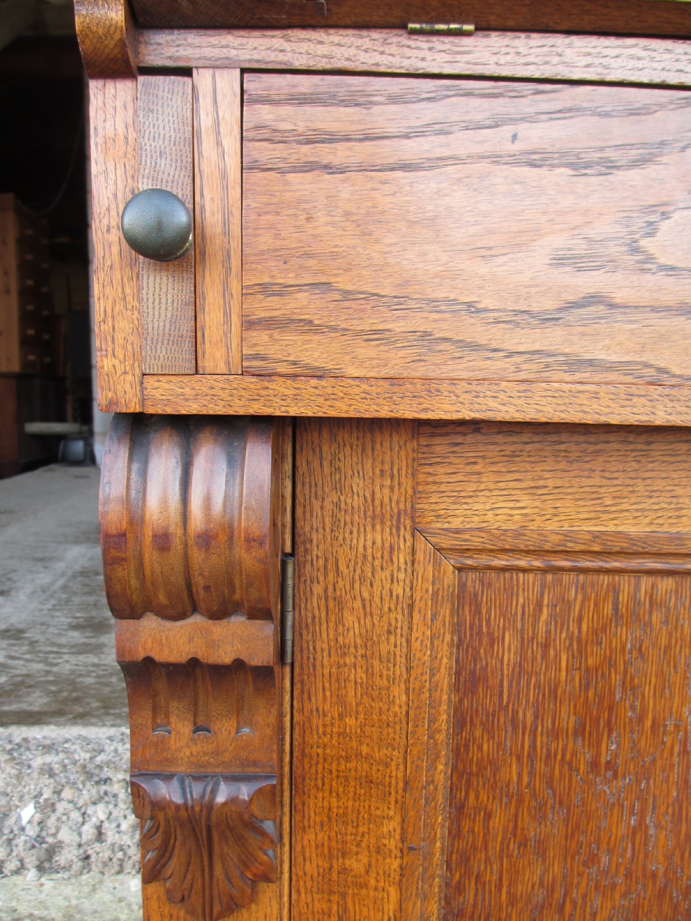 An Edwardian golden oak bureau bookcase featuring a two-door glazed upper section, a fall-front slanted writing desk, and a lower cabinet base with carved supports. View IX