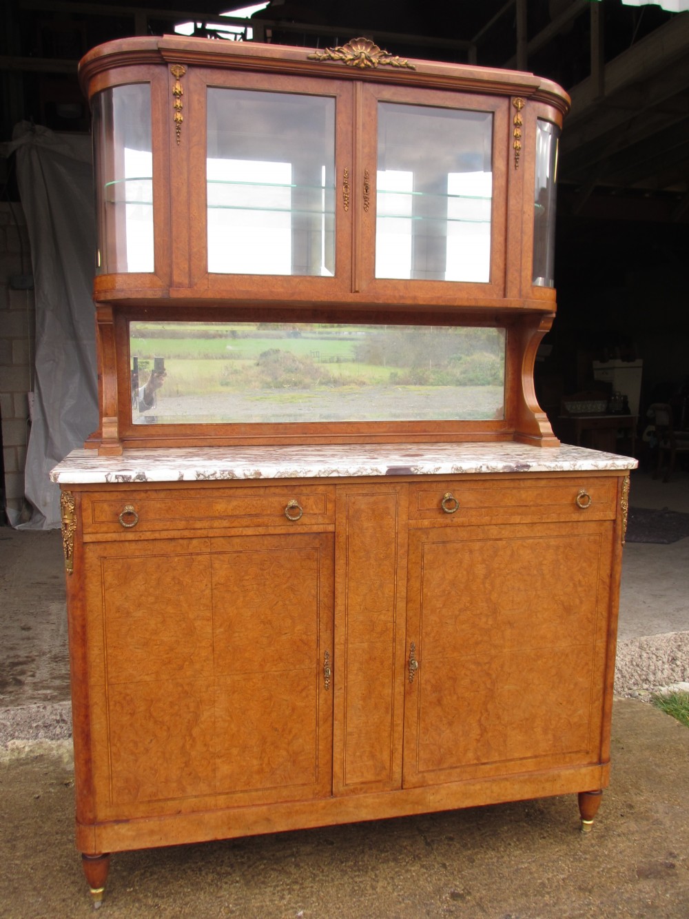 An antique French birds eye maple buffet featuring a marble top, a mirrored splashback, an upper glazed display cabinet with ormolu mounts, and two lower cupboard doors.