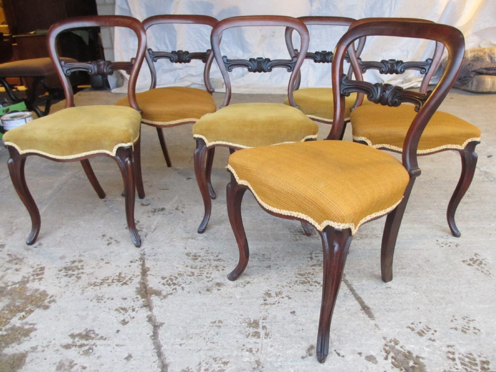 A set of six Victorian rosewood balloon back dining chairs with carved waist rails, yellow upholstered serpentine seats, and cabriole legs. View II