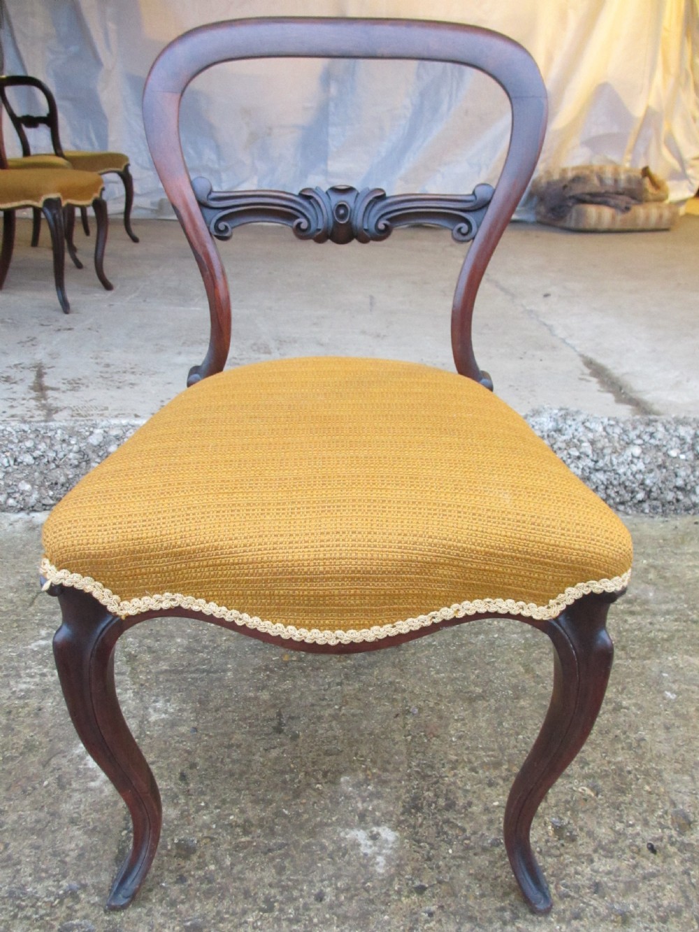 A set of six Victorian rosewood balloon back dining chairs with carved waist rails, yellow upholstered serpentine seats, and cabriole legs. View IV