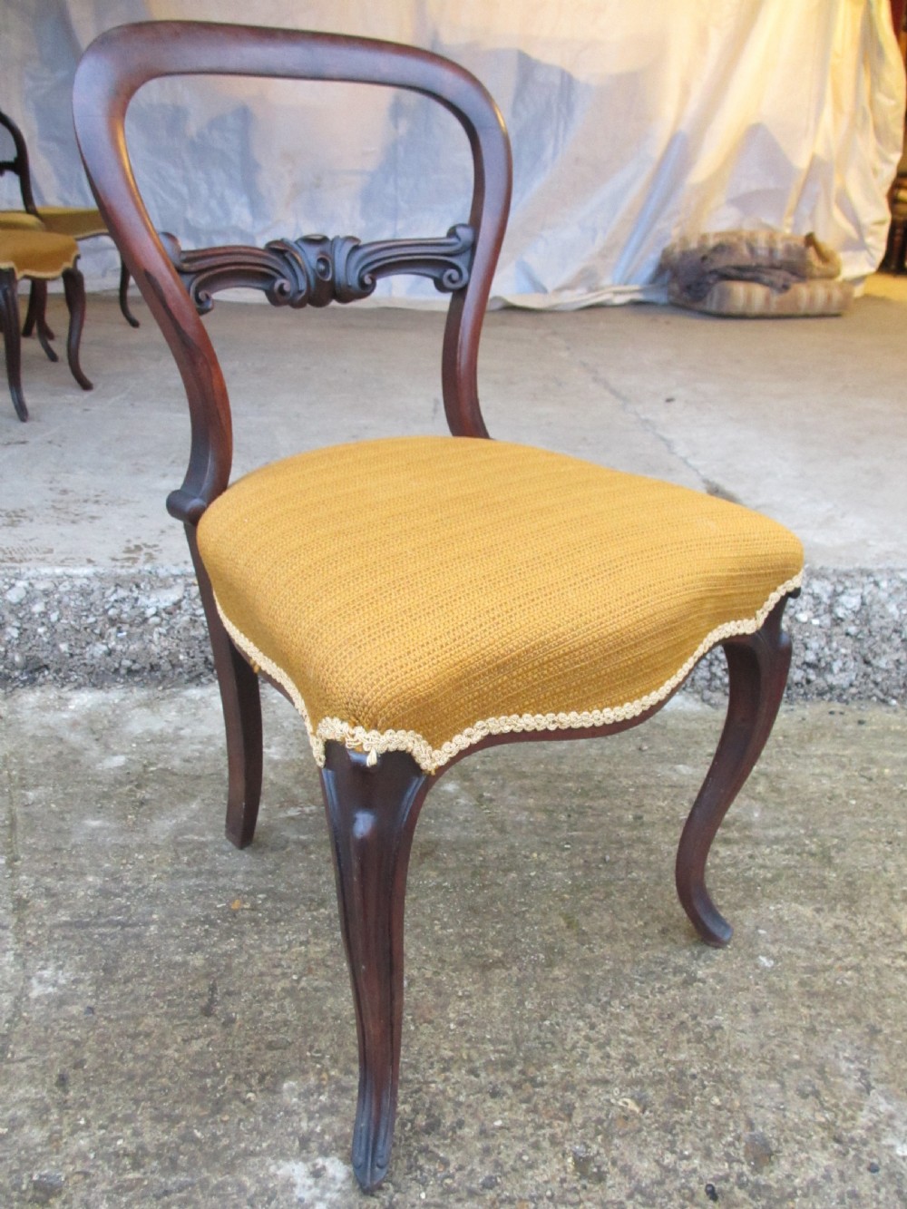 A set of six Victorian rosewood balloon back dining chairs with carved waist rails, yellow upholstered serpentine seats, and cabriole legs. View V