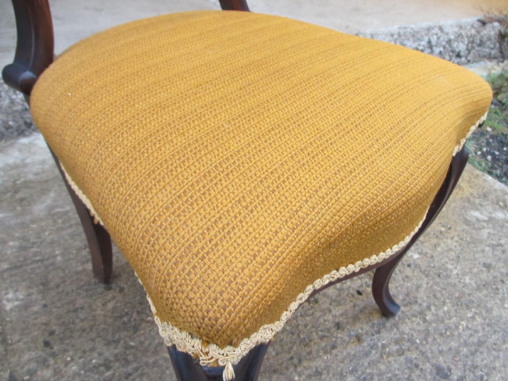 A set of six Victorian rosewood balloon back dining chairs with carved waist rails, yellow upholstered serpentine seats, and cabriole legs. View VI