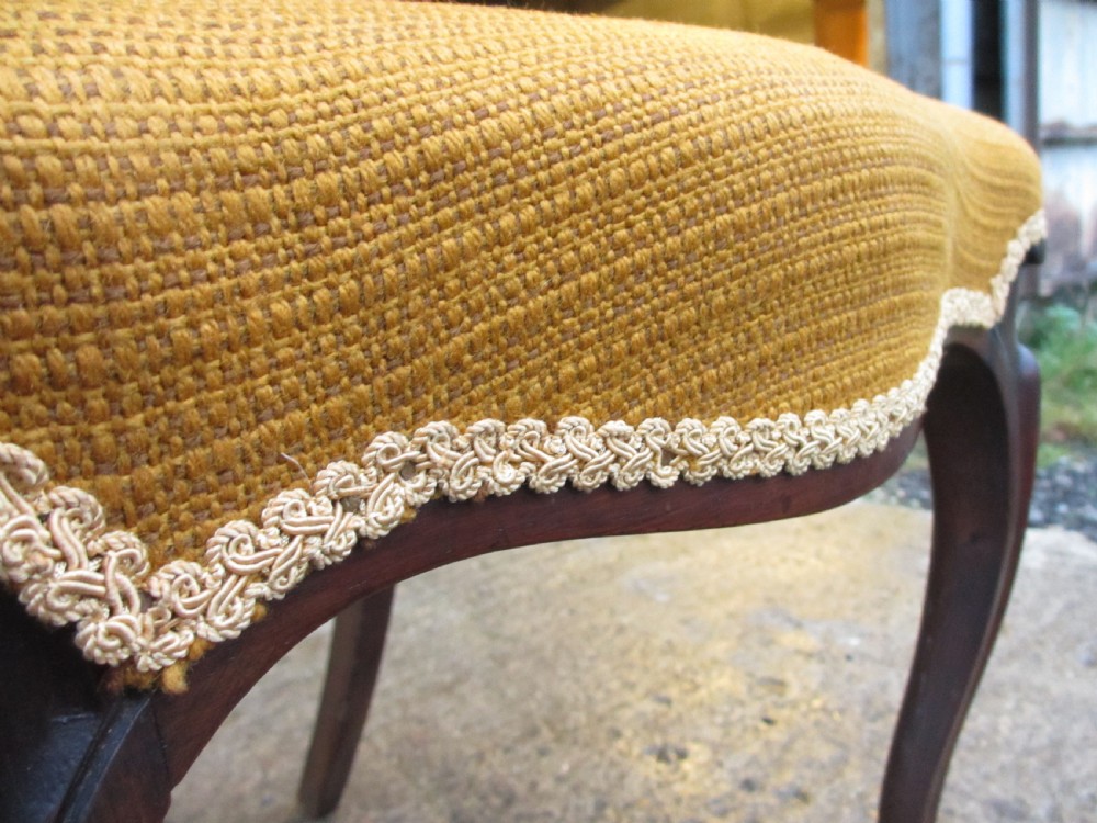A set of six Victorian rosewood balloon back dining chairs with carved waist rails, yellow upholstered serpentine seats, and cabriole legs. View X