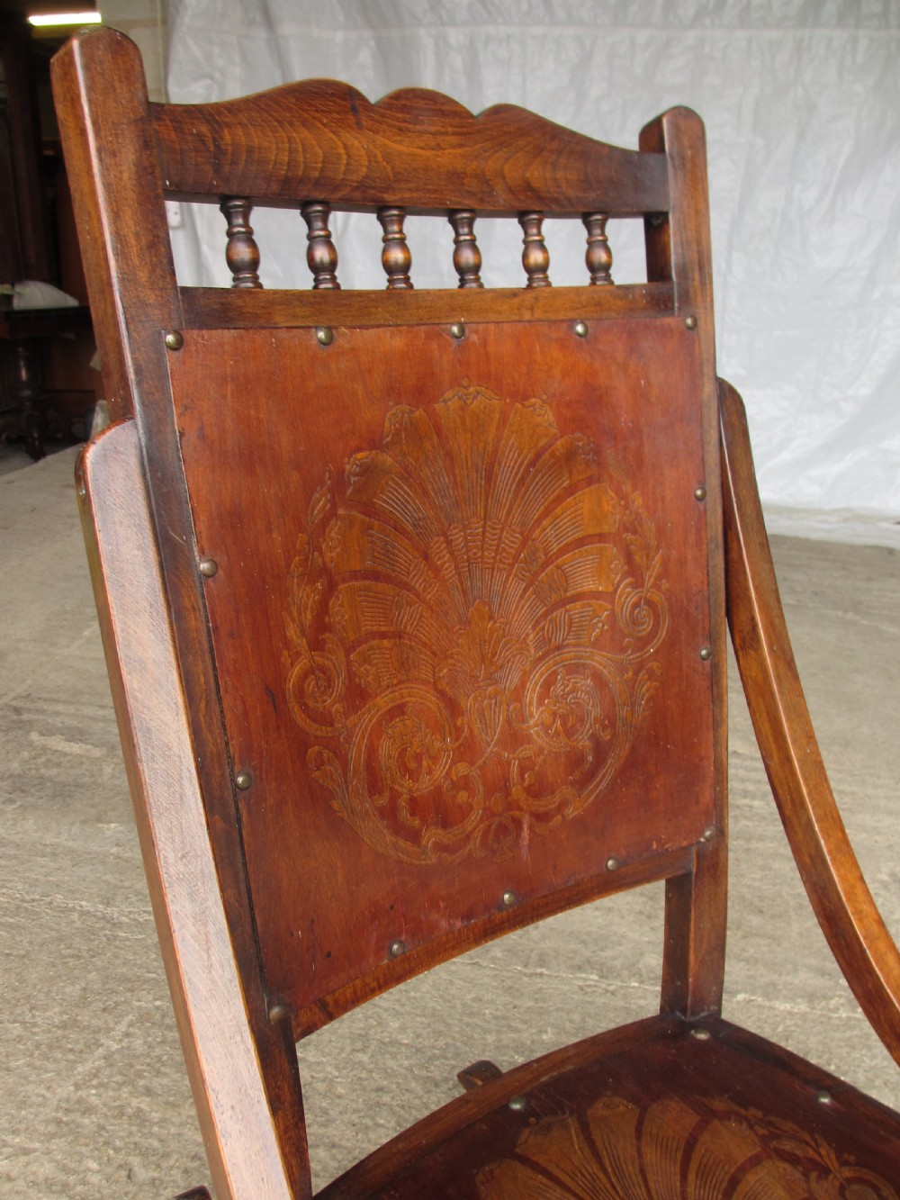 A Victorian oak and beech rocking chair featuring turned spindles, a carved shell pattern on the backrest and seat, and decorative metal studs. View III