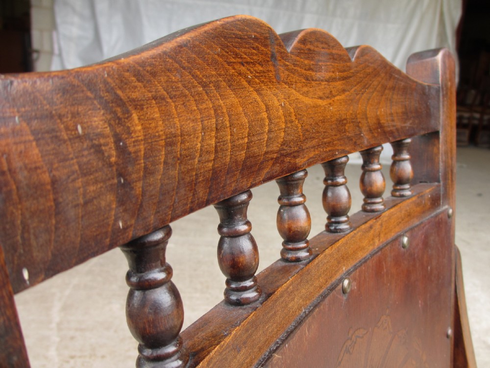 A Victorian oak and beech rocking chair featuring turned spindles, a carved shell pattern on the backrest and seat, and decorative metal studs. View IV