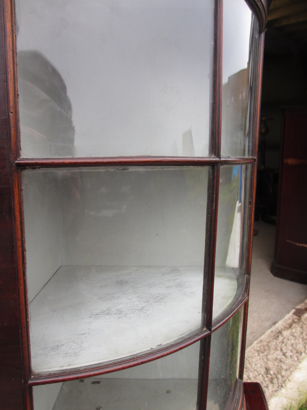 A two-piece flame mahogany corner cabinet featuring a broken pediment top, an upper glazed door, and a lower bow-front cupboard door supported by cabriole legs. View VI