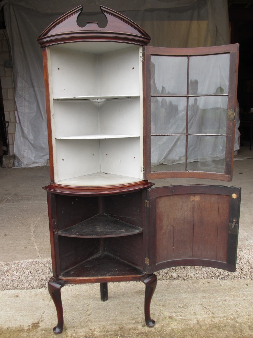 A two-piece flame mahogany corner cabinet featuring a broken pediment top, an upper glazed door, and a lower bow-front cupboard door supported by cabriole legs. View VIII