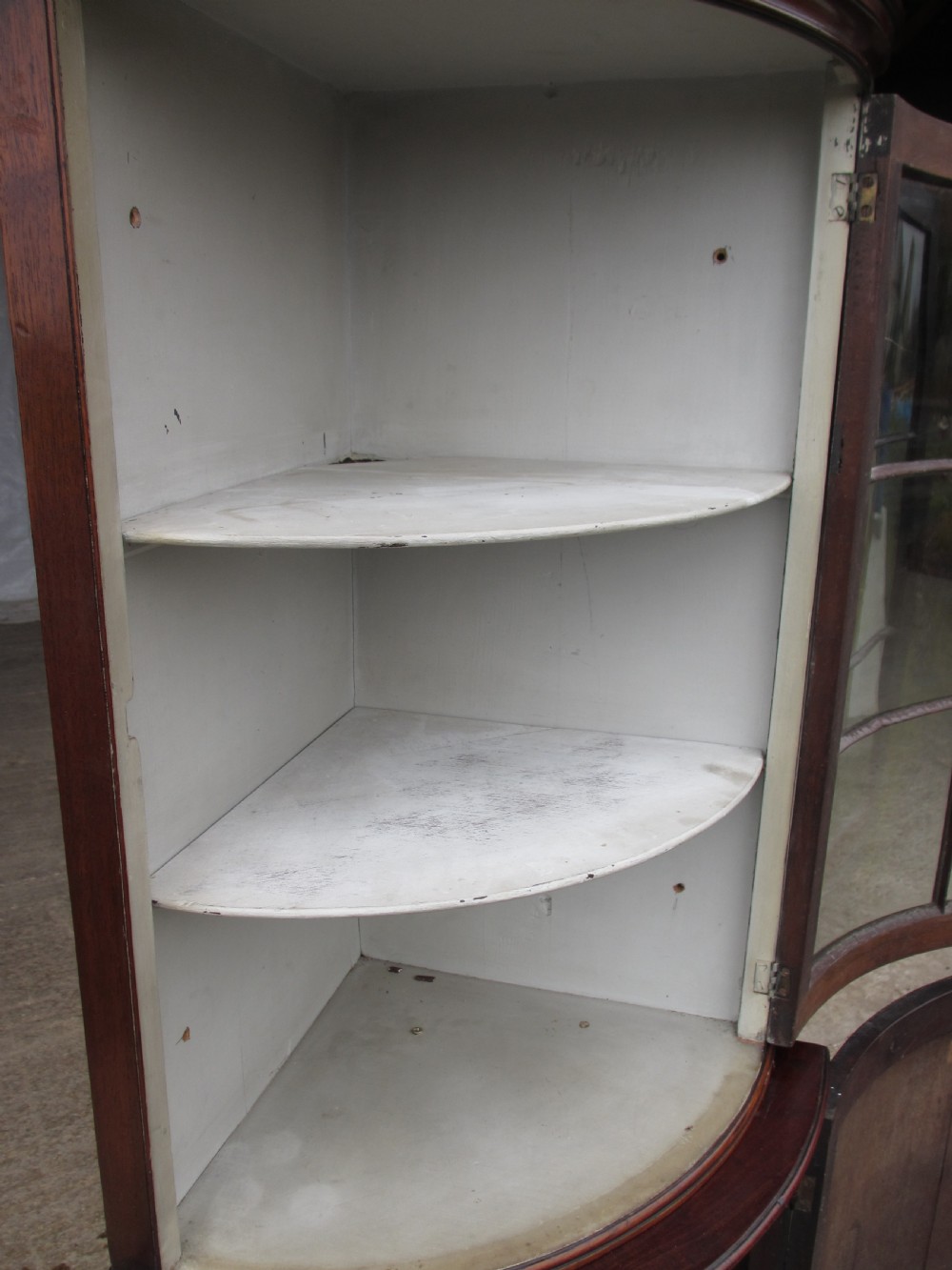 A two-piece flame mahogany corner cabinet featuring a broken pediment top, an upper glazed door, and a lower bow-front cupboard door supported by cabriole legs. View IX