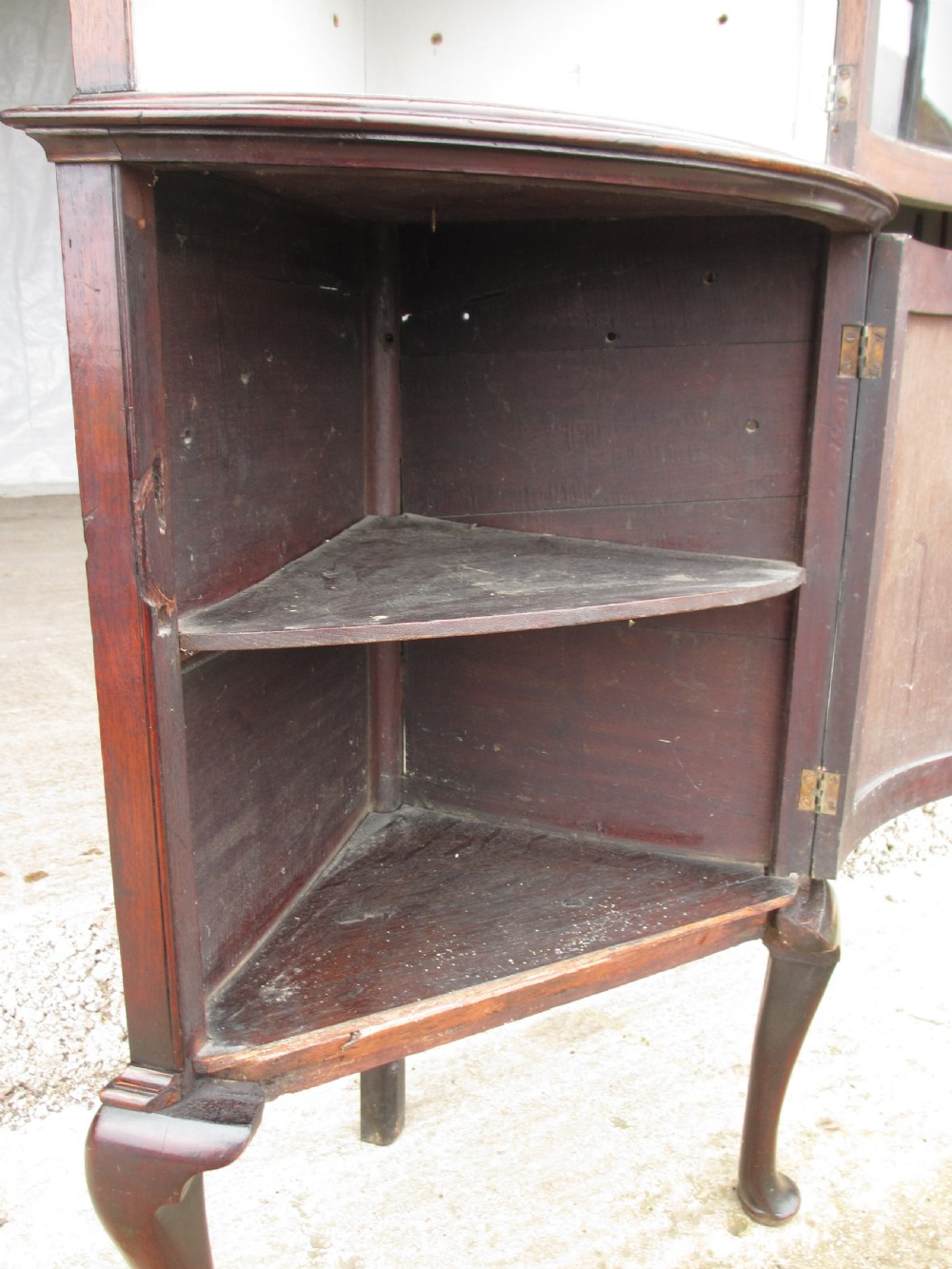 A two-piece flame mahogany corner cabinet featuring a broken pediment top, an upper glazed door, and a lower bow-front cupboard door supported by cabriole legs. View X