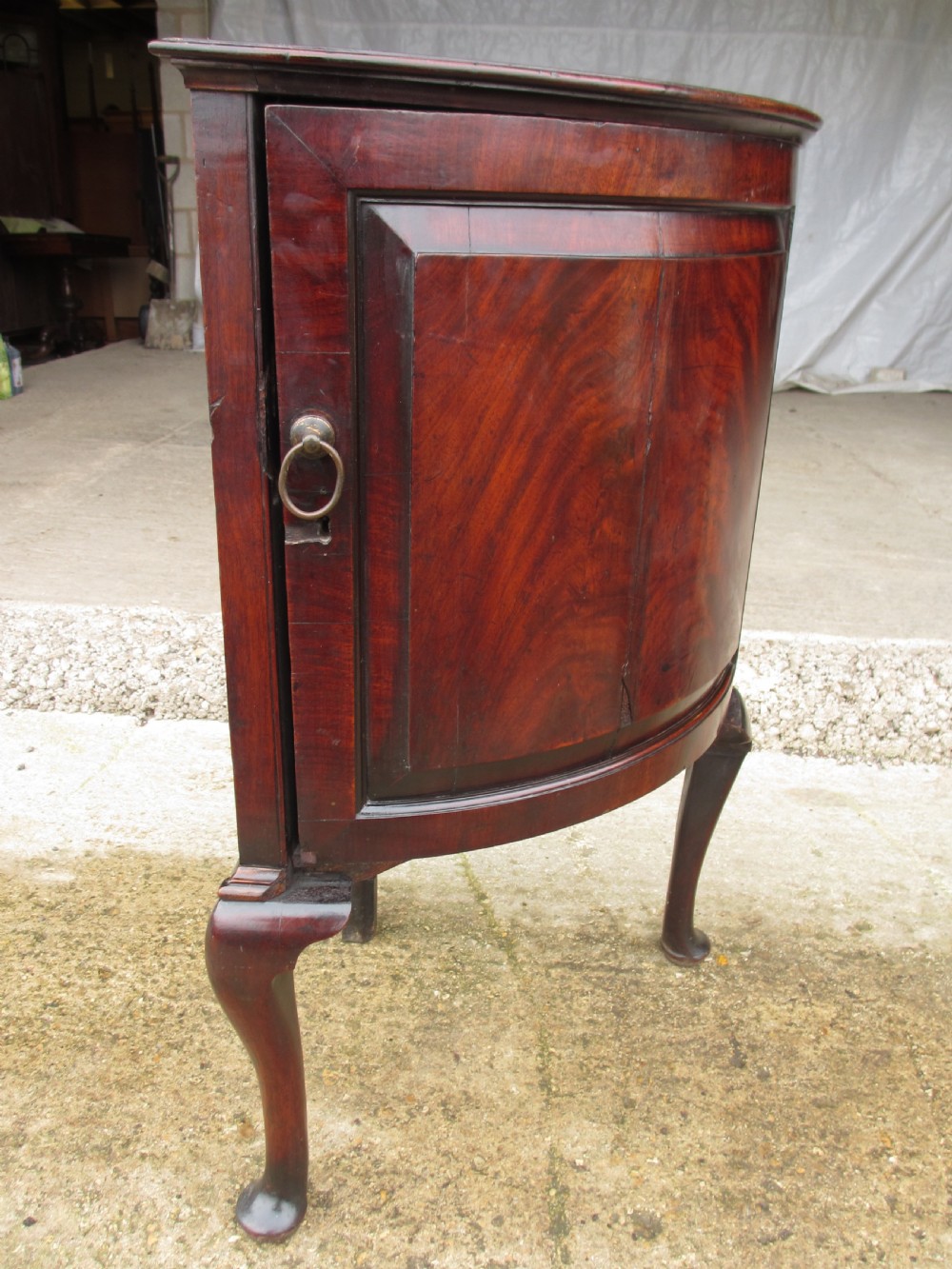 A two-piece flame mahogany corner cabinet featuring a broken pediment top, an upper glazed door, and a lower bow-front cupboard door supported by cabriole legs. View XII
