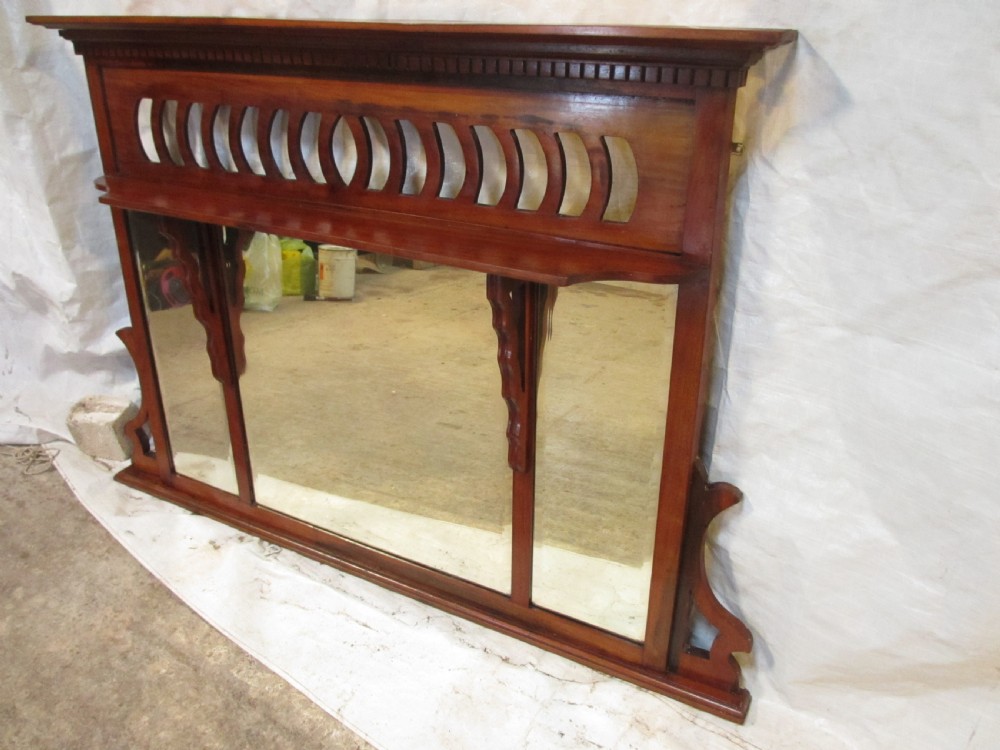 A Victorian mahogany triptych overmantel mirror featuring three glass panels, a fretted top frieze with crescent cut-outs, decorative side brackets, and a moulded cornice. View III