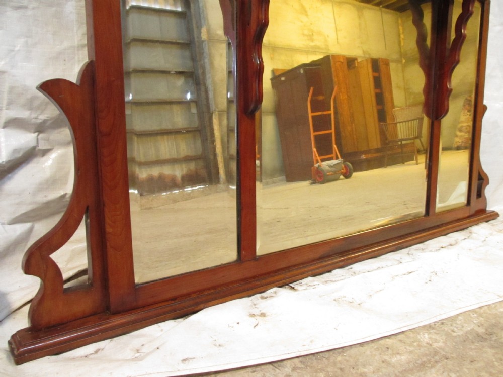 A Victorian mahogany triptych overmantel mirror featuring three glass panels, a fretted top frieze with crescent cut-outs, decorative side brackets, and a moulded cornice. View V