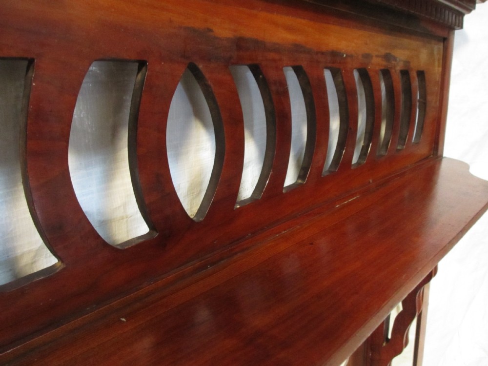 A Victorian mahogany triptych overmantel mirror featuring three glass panels, a fretted top frieze with crescent cut-outs, decorative side brackets, and a moulded cornice. View VIII