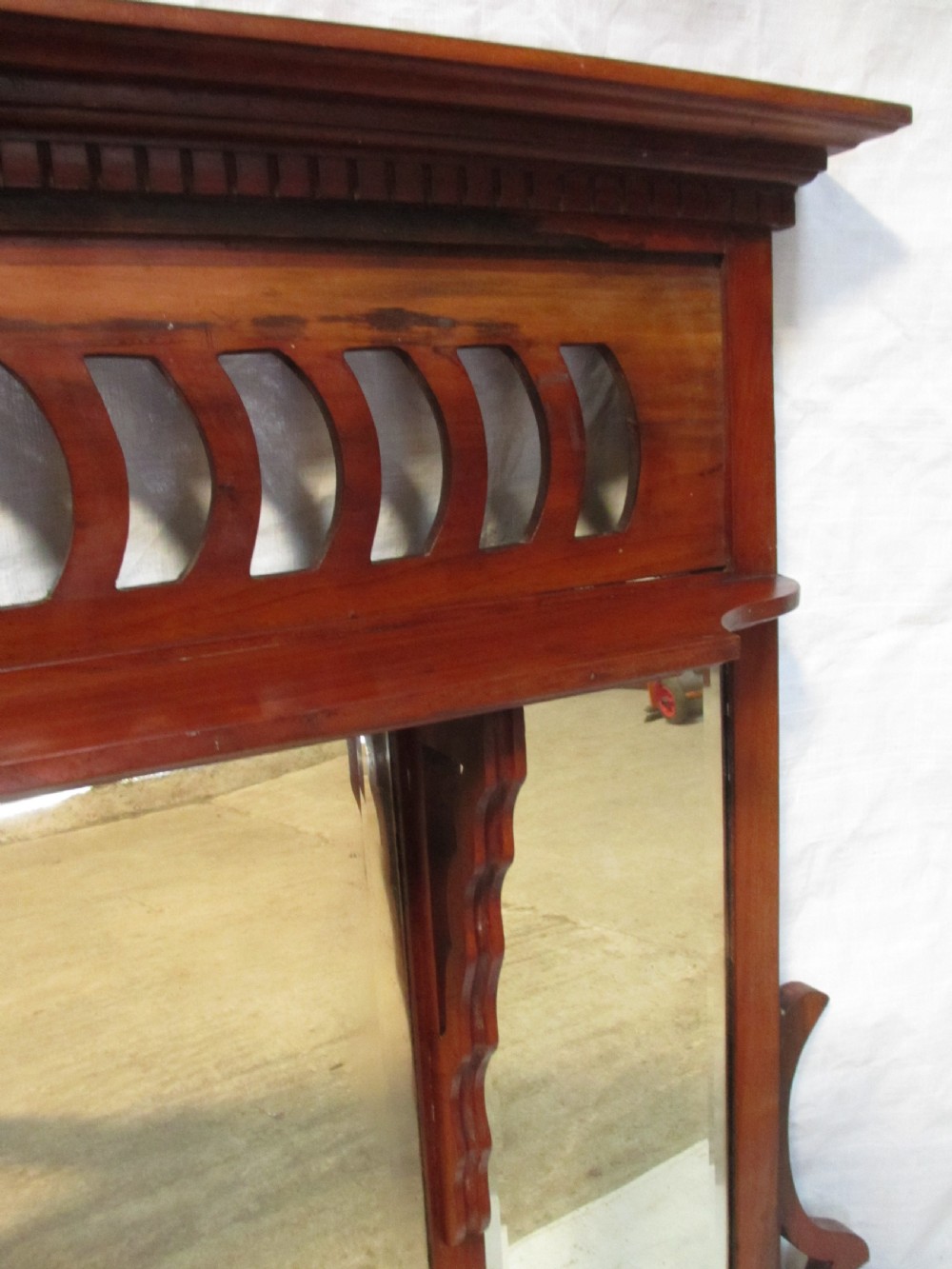 A Victorian mahogany triptych overmantel mirror featuring three glass panels, a fretted top frieze with crescent cut-outs, decorative side brackets, and a moulded cornice. View XI