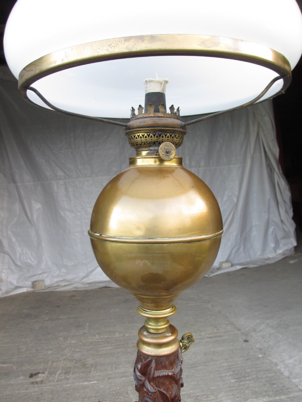 A Victorian Anglo-Burmese carved padouk wood and brass floor oil lamp with mythical dragon legs, a carved column, a brass reservoir, and a white glass shade. View III