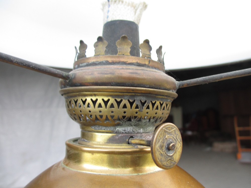 A Victorian Anglo-Burmese carved padouk wood and brass floor oil lamp with mythical dragon legs, a carved column, a brass reservoir, and a white glass shade. View IV