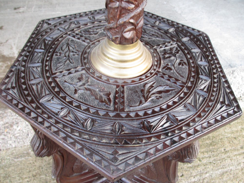 A Victorian Anglo-Burmese carved padouk wood and brass floor oil lamp with mythical dragon legs, a carved column, a brass reservoir, and a white glass shade. View VII
