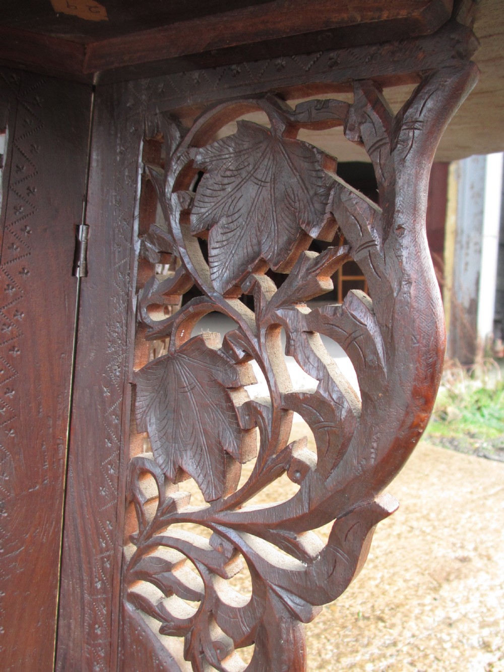 An Anglo-Indian carved teak occasional table with a scalloped circular top, floral inlay centre, and a folding fretted base. View V