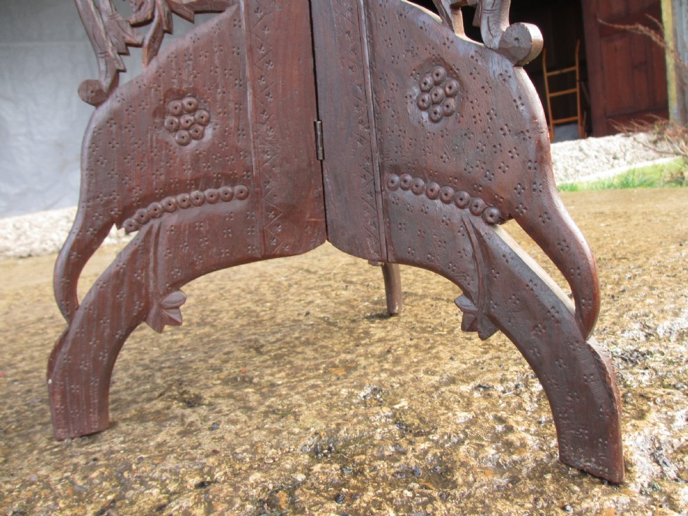 An Anglo-Indian carved teak occasional table with a scalloped circular top, floral inlay centre, and a folding fretted base. View VI
